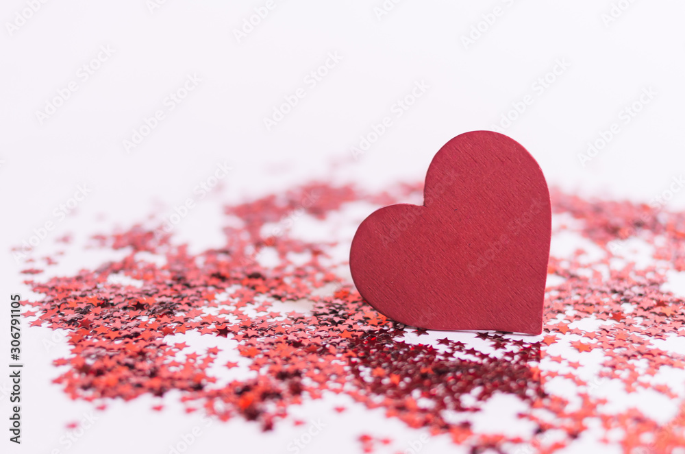 Fototapeta premium red heart shape wooden piece on pink background with red glitter