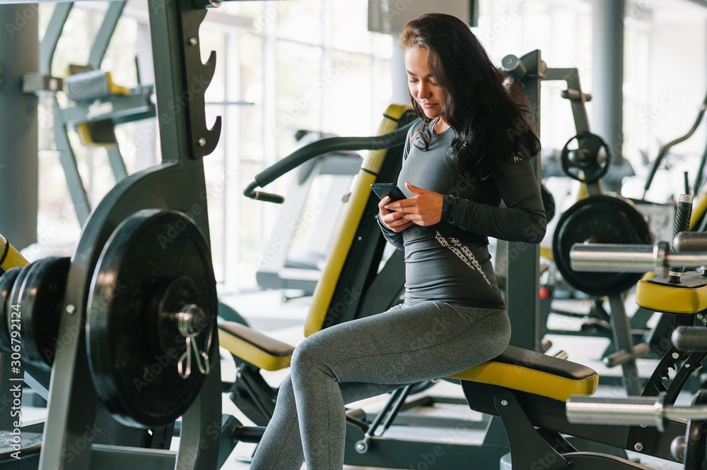 Gorgeous young woman texting and social networking while in a gym Gorgeous young woman texting and social networking while in a gym