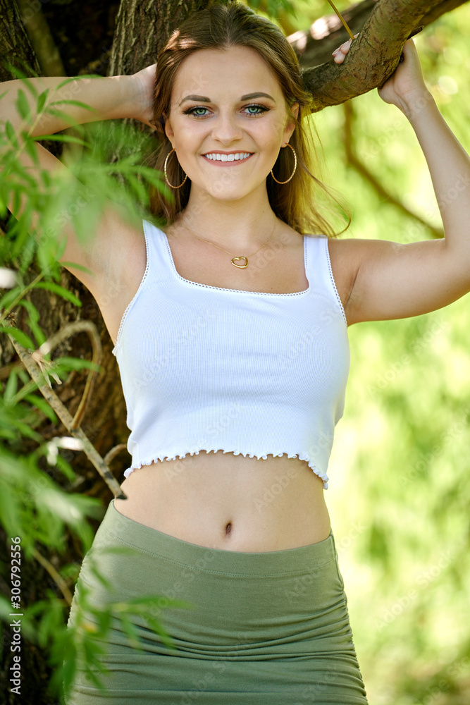 Stunning young female fashion model poses in park near willow tree Ð summer smiling.. Stunning young female fashion model poses in park near willow tree Ð summer smiling..