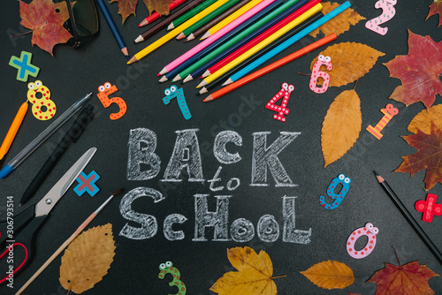 Back to school concept. School and office supplies on blackboard background.