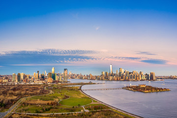 Aerial view of New York City and Jersey City skylines together with Ellis Island, as viewed from above Liberty State Park, in New Jersey, at dusk.
