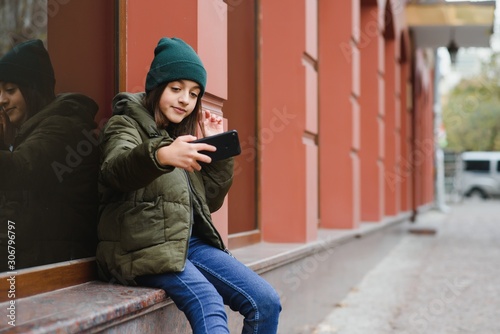 stylish beautiful teen girl on the street in a hat and jacket