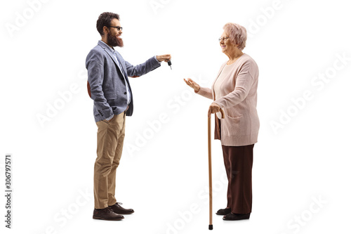 Bearded man giving car keys to an elderly woman with a walking cane