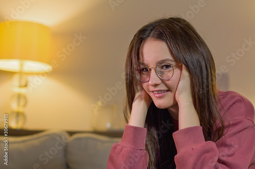Portrait of beauty teenager beautiful beautiful girl with long brown hair sitting on the couch in the shadow of the room