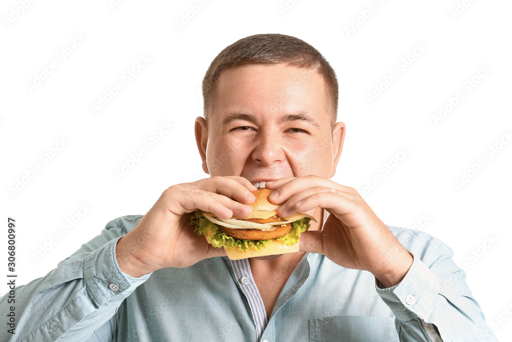Overweight man eating burger against white background Overweight man eating burger against white background