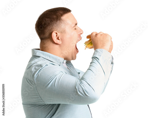 Overweight man eating burge...