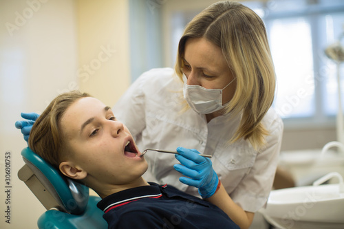 Dentist woman doing teeth checkup of guy in a dental chair at medical clinic. Health care and stomatology medicine concept.