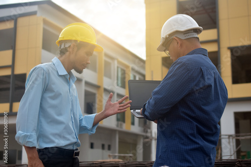 Two Engineering use computer notebook presentation at work place building estate construction background