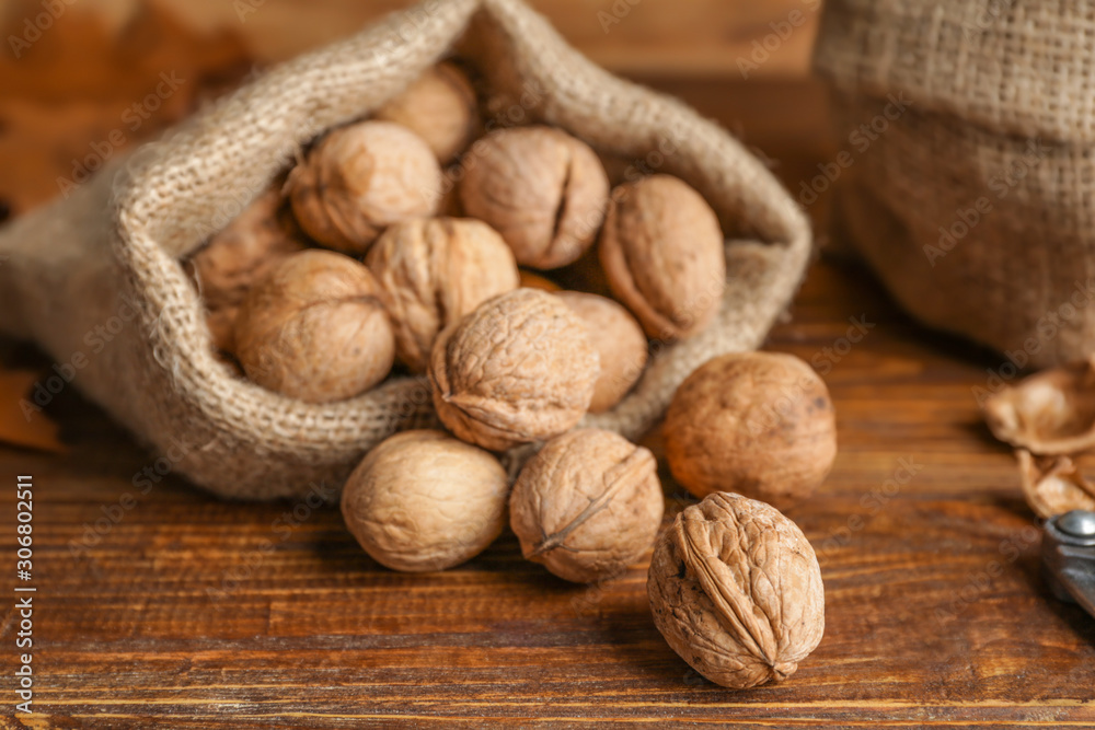 Sack with tasty walnuts on wooden table Sack with tasty walnuts on wooden table