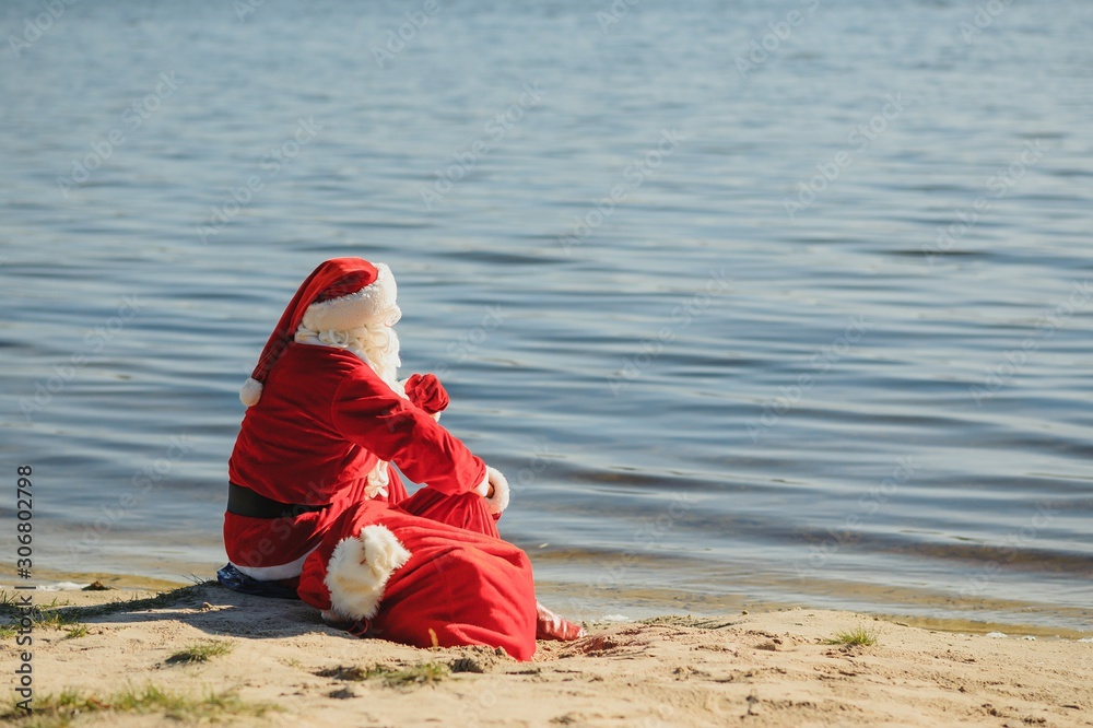 Santa Claus in swimming suit walking along the beach Santa Claus in swimming suit walking along the beach