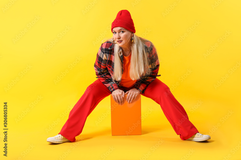 Fashionable mature woman on color background