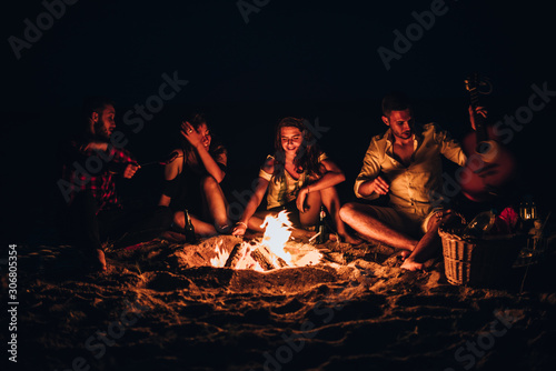 Friends roasting sausage at the beach in the night