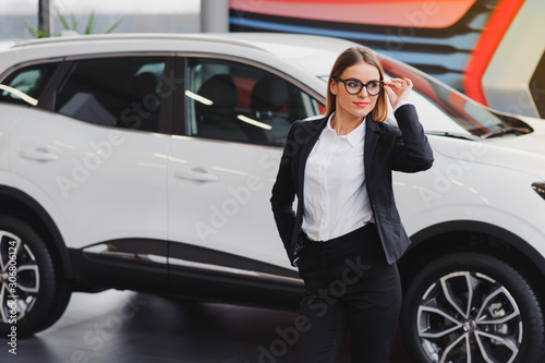 auto business, car sale, consumerism and people concept - happy woman taking car key from dealer in auto show or salon. © Serhii