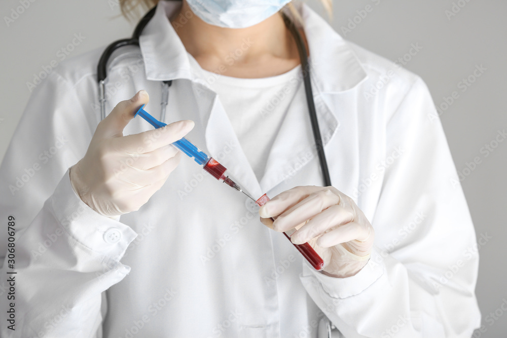 Laboratory assistant holding syringe and test tube with blood sample in clinic, closeup Laboratory assistant holding syringe and test tube with blood sample in clinic, closeup