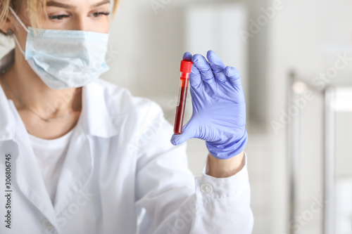 Laboratory assistant holding test tube with blood sample in clinic