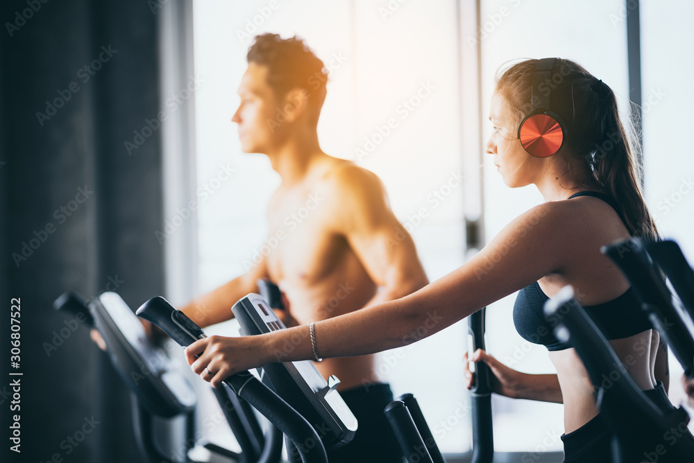 Naklejka premium Young women wear headphones to exercise in the sport gym