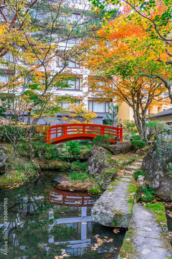 Red bridge in japanese green park with autumn color leaves, Japanese autumn fall