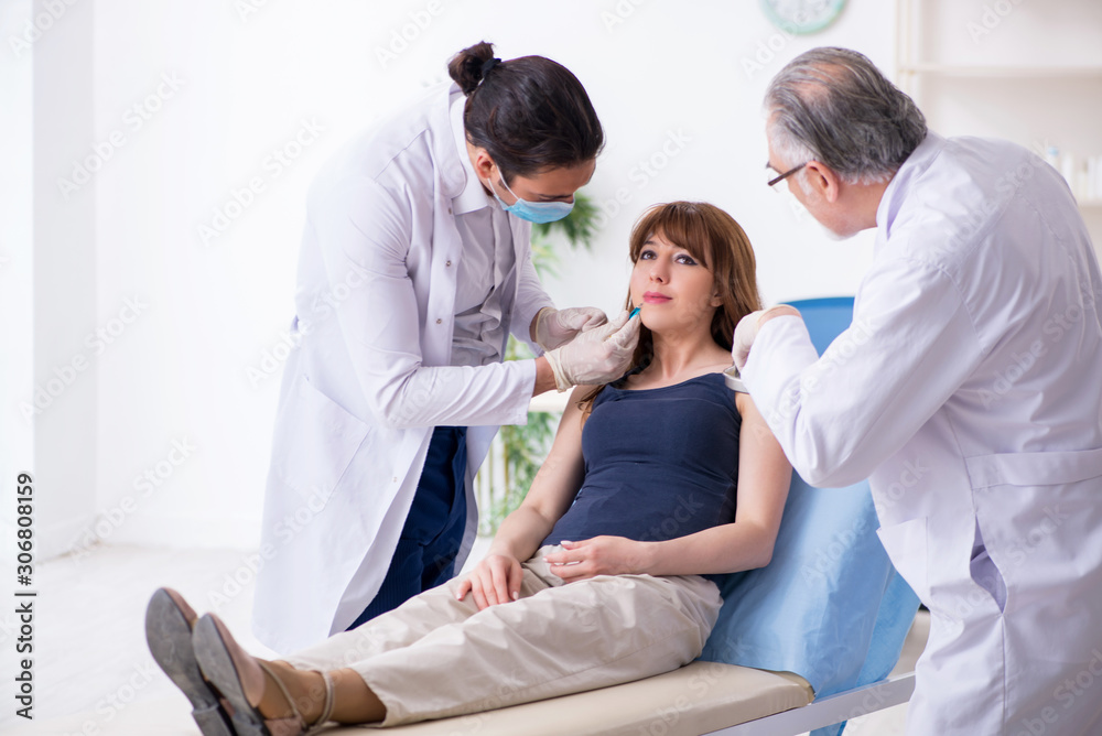 Fototapeta premium Two male doctors and young woman in plastic surgery concept