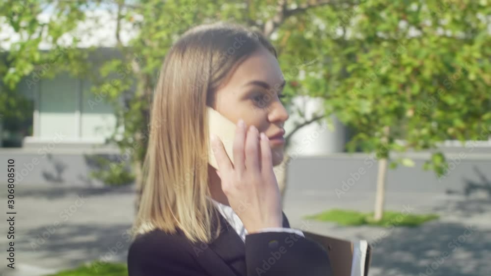 Up section shot of young successful businesswoman walking through the city and talking on mobile phone with her employee Up section shot of young successful businesswoman walking through the city and talking on mobile phone with her employee