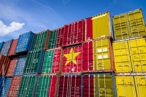 The national flag of Cameroon on a large number of metal containers for storing goods stacked in rows on top of each other. Conception of storage of goods by importers, exporters