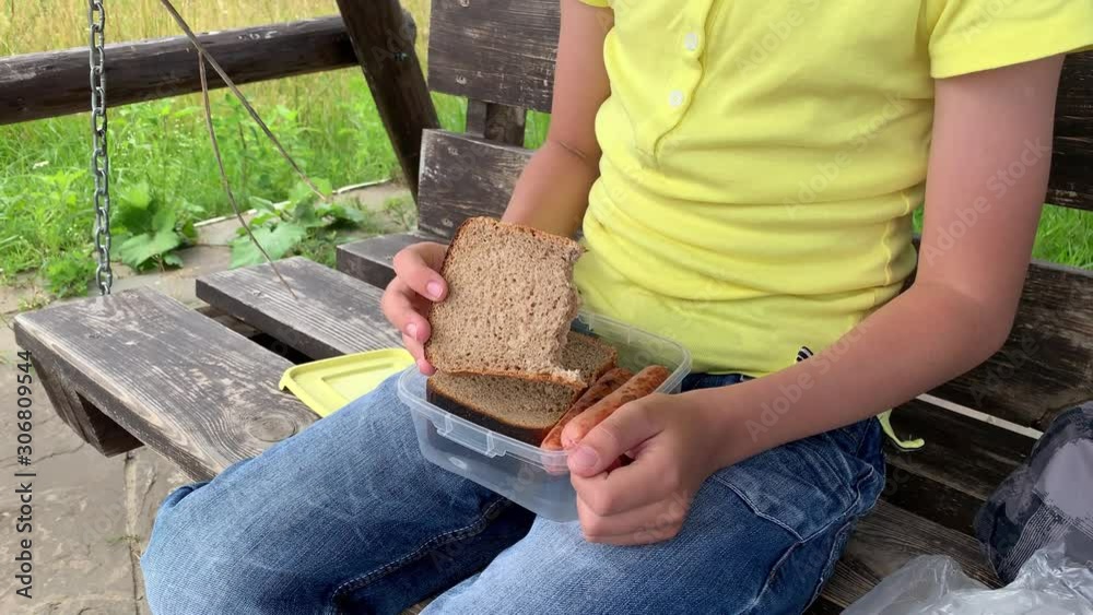 A preteen boy eating a piece of whole grain brown bread from ...