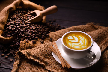 Foto auf Leinwand Küche Tasse Kaffee Latte und Kaffeebohnen im Leinensack auf altem Holzhintergrund  © amenic181