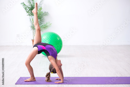 Schilderij op canvas Little girl gymnast doing exercises indoors