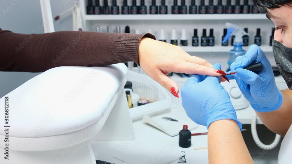 Manicurist is applying gel polish to the nails of a client in a beauty salon. Build up nails. Manicure