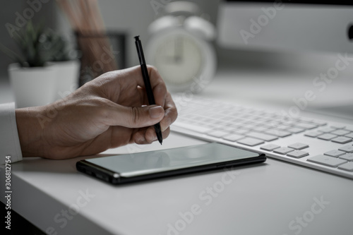 Close up shot of businessman working in office holding smart phone with blank screen