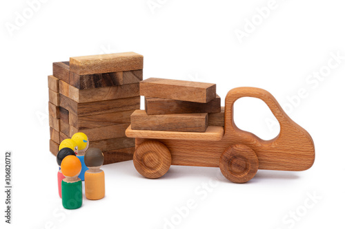 The wooden toy of the truck brought the building material in the form of logs to the construction site. Images of builders from children's toys. Construction and construction site concept