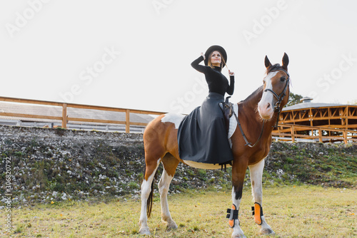Happy fashionable young woman posing with a horse on the beach © Serhii