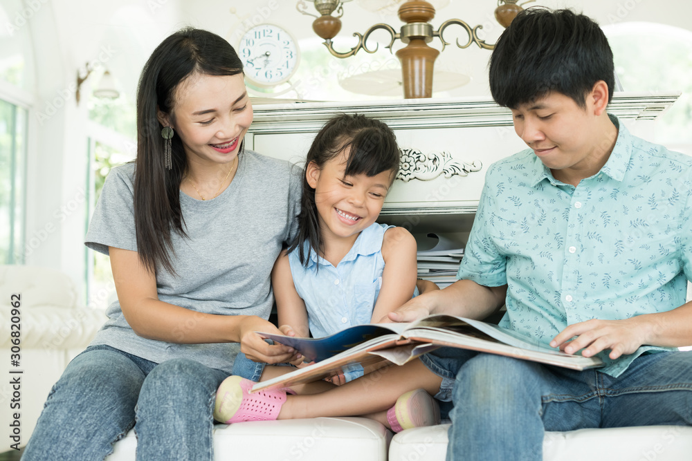 Fototapeta premium Happy family at home. Mother and father reading their daughter book story.