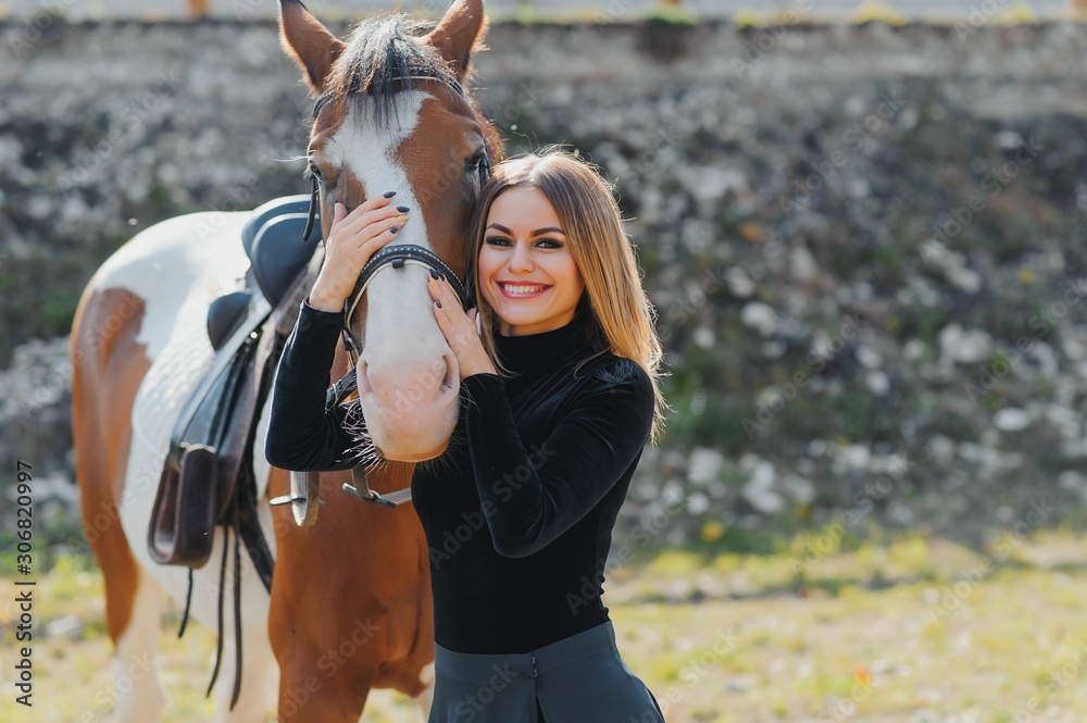 Obraz premium Young woman physiotherapist taking care a brown horse. Woman making a treatment in the shoulder, crest, forehead, muzzle and chin groove.