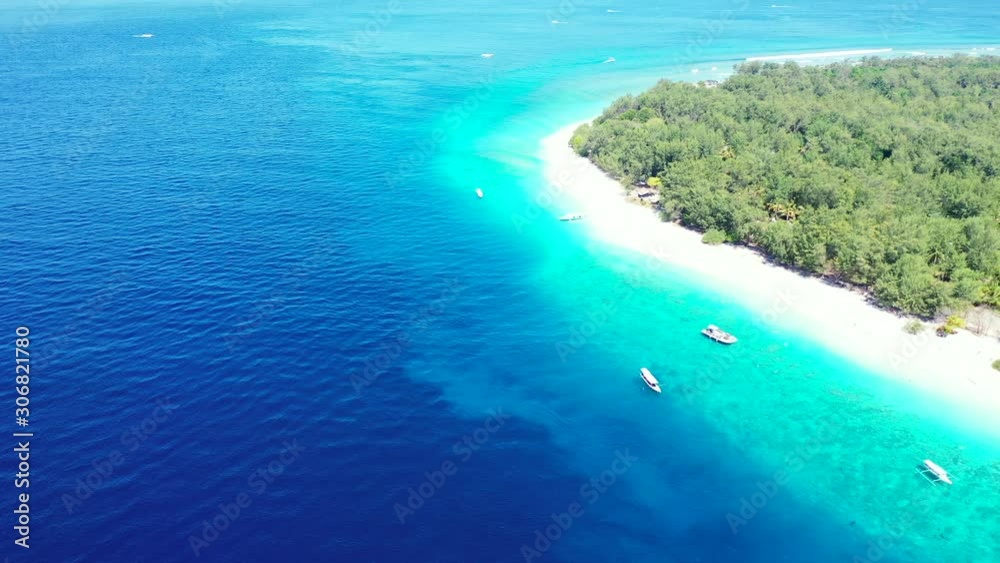 Vivid colors of deep blue ocean and bright turquoise lagoon around tropical island with white beach and green vegetation in Indonesia Vivid colors of deep blue ocean and bright turquoise lagoon around tropical island with white beach and green vegetation in Indonesia