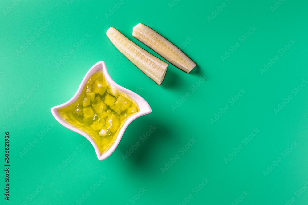 Cucumber jam in a bowl on a bright green background