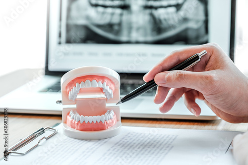 Dentist with male patient learning how to teeth in dental office