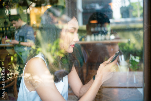 Beautiful asian women use smartphone drinking coffe in cafe