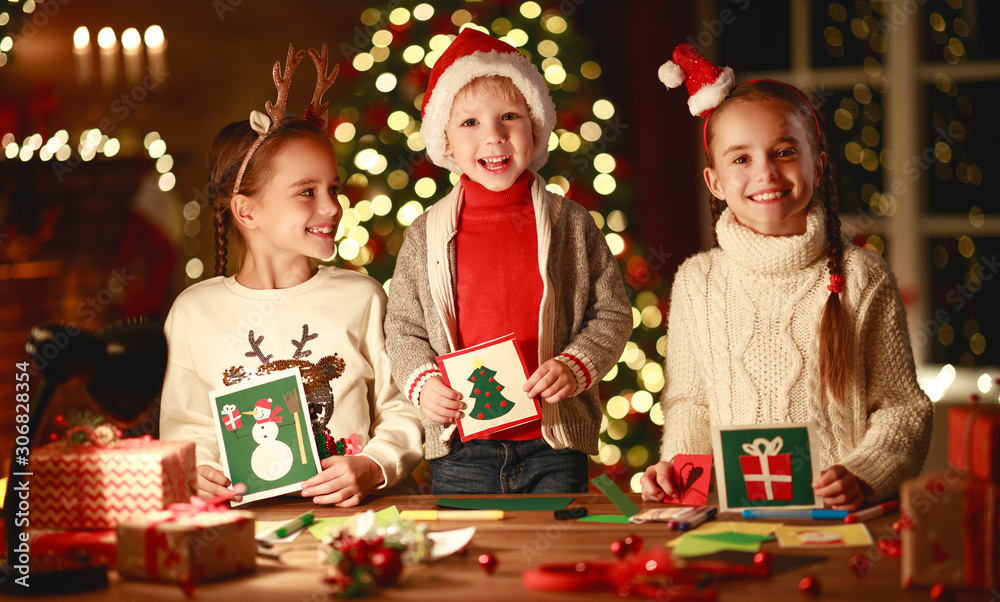 happy friends kids draw decorations and write letter to Santa near Christmas tree happy friends kids draw decorations and write letter to Santa near Christmas tree