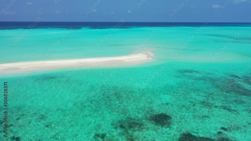Bright turquoise lagoon with calm clear water over coral reefs and pebbles around an exposed sandy stripe under blue sky in Turks and Caicos Bright turquoise lagoon with calm clear water over coral reefs and pebbles around an exposed sandy stripe under blue sky in Turks and Caicos
