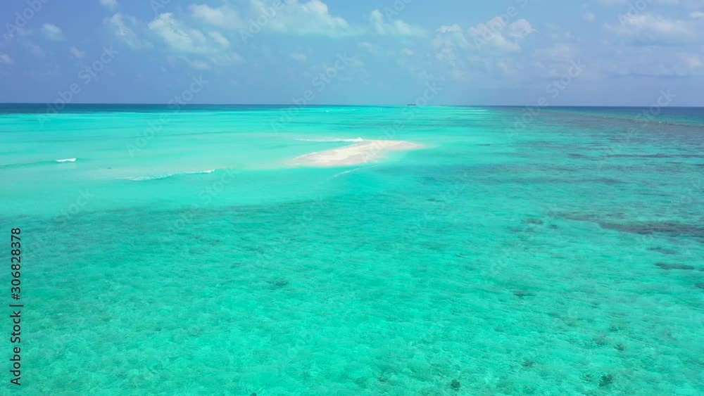 White sandy dune covering from rising water of large turquoise lagoon around Ari atoll in the middle of deep Indian ocean on a bright sky background White sandy dune covering from rising water of large turquoise lagoon around Ari atoll in the middle of deep Indian ocean on a bright sky background