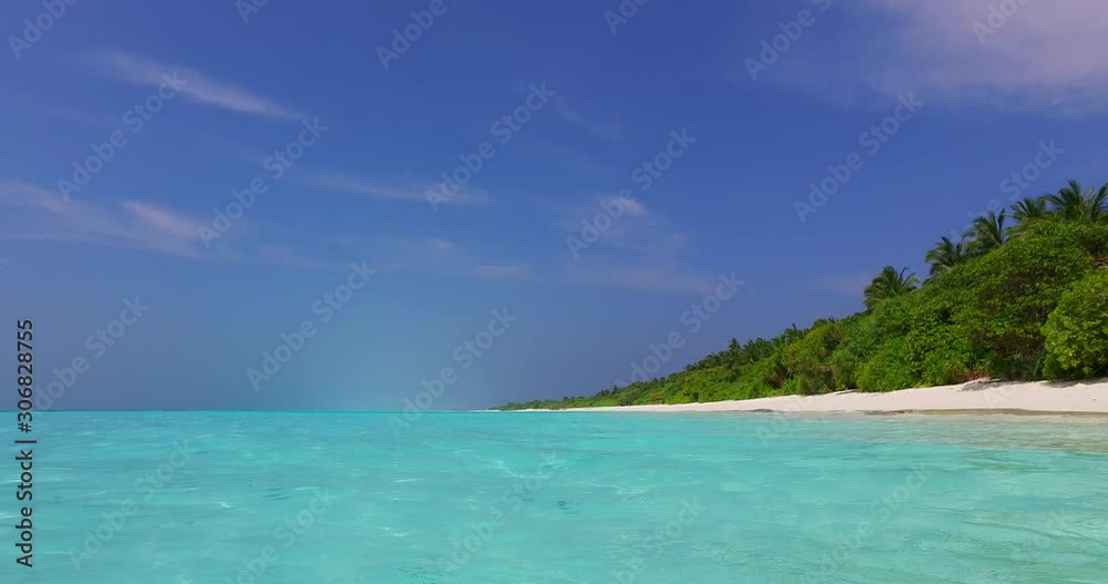 Close up of azure clear water flows washing white sand of pristine beach on tropical island with palms and lush vegetation under purple sky of morning Close up of azure clear water flows washing white sand of pristine beach on tropical island with palms and lush vegetation under purple sky of morning