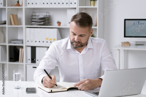 Director of business company organizing work or writing down plan for the day