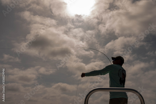 Silhouette of a fisherman against a cloudy sky.