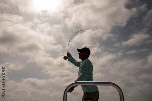 Silhouette of a fisherman against a cloudy sky.