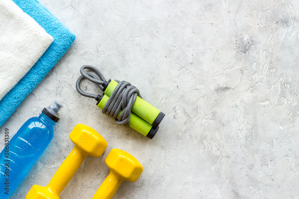 Fototapeta premium Gym equipment - dumbbells, jump rope - frame on grey background top-down copy space