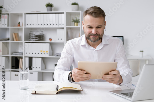 Wallpaper Mural Serious businessman with touchpad watching online video training or conference Torontodigital.ca