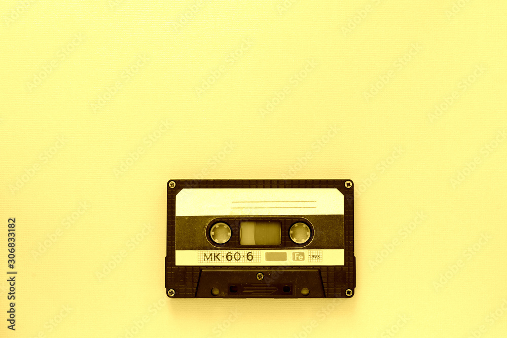 Old audio tape cassette, top view. Old technology concept. Yellow color toned