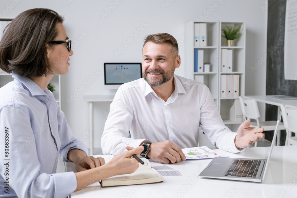 Happy male broker pointing at laptop display while making presentation Happy male broker pointing at laptop display while making presentation