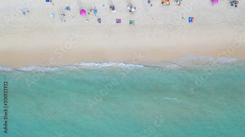 Aerial top view, the beach in day time, At Surin beach in Phuket - Thailand. Colorful umbrellas on the sand, make layer of sea water with some wave. Some people lie on beach