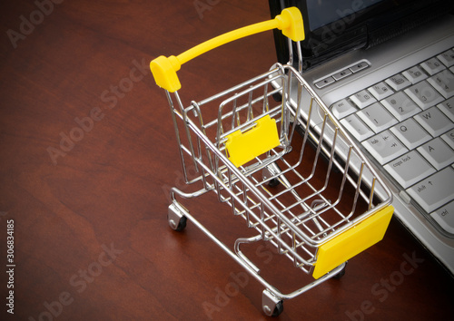 Shopping cart and laptop computer. Buy online concept.